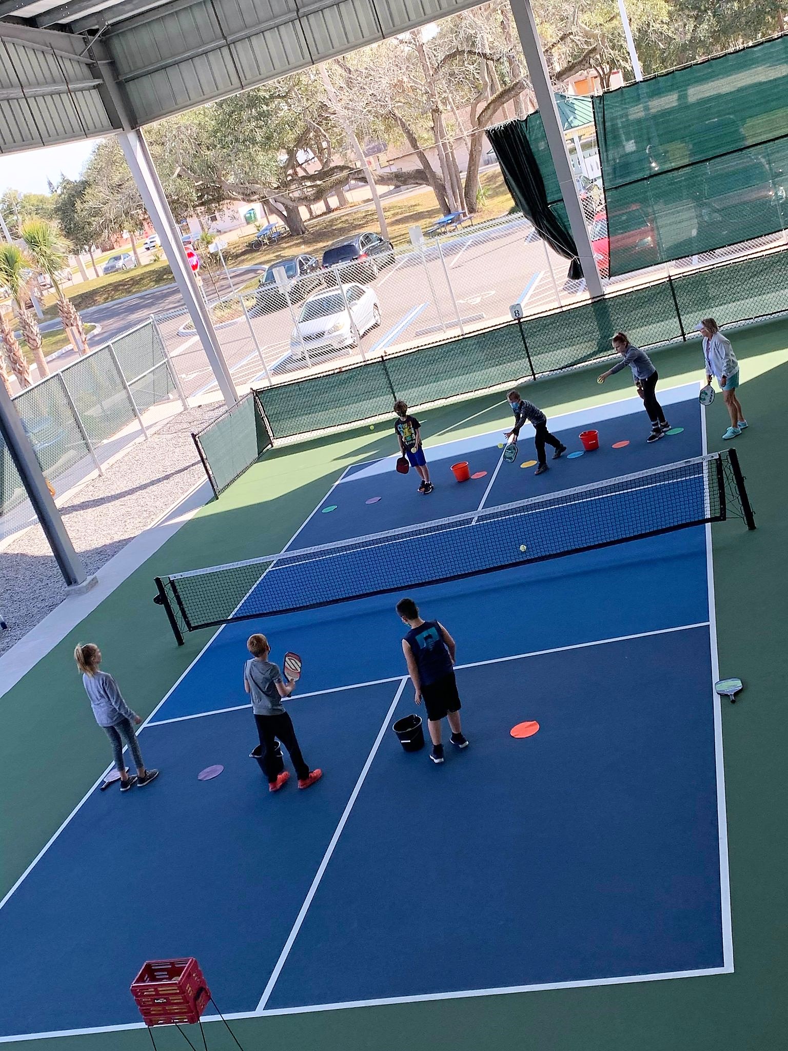 Young participants practicing pickleball skills on covered courts